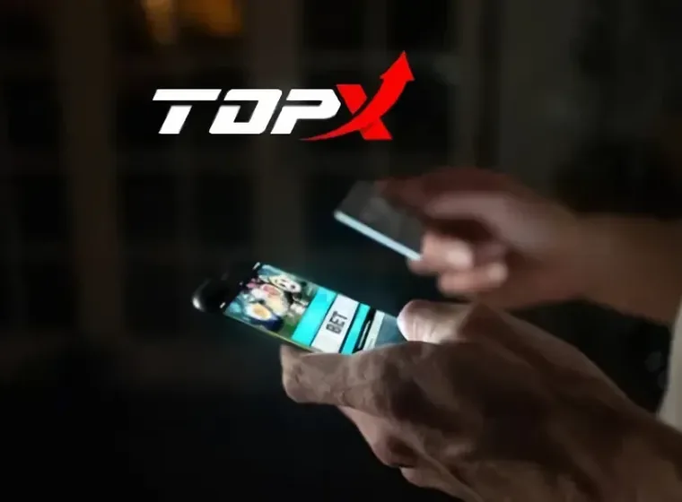 Duas mãos segurando celulares acesos em ambiente escuro